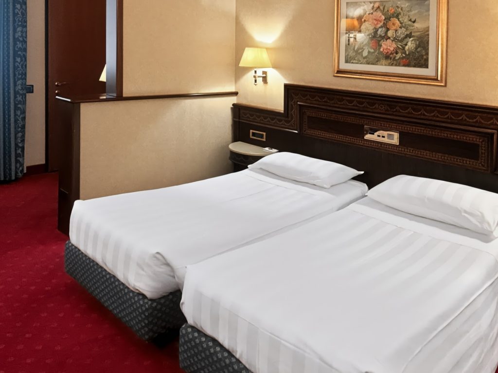 Classic Room con due letti singoli e moquette rossa all'Hotel Luna