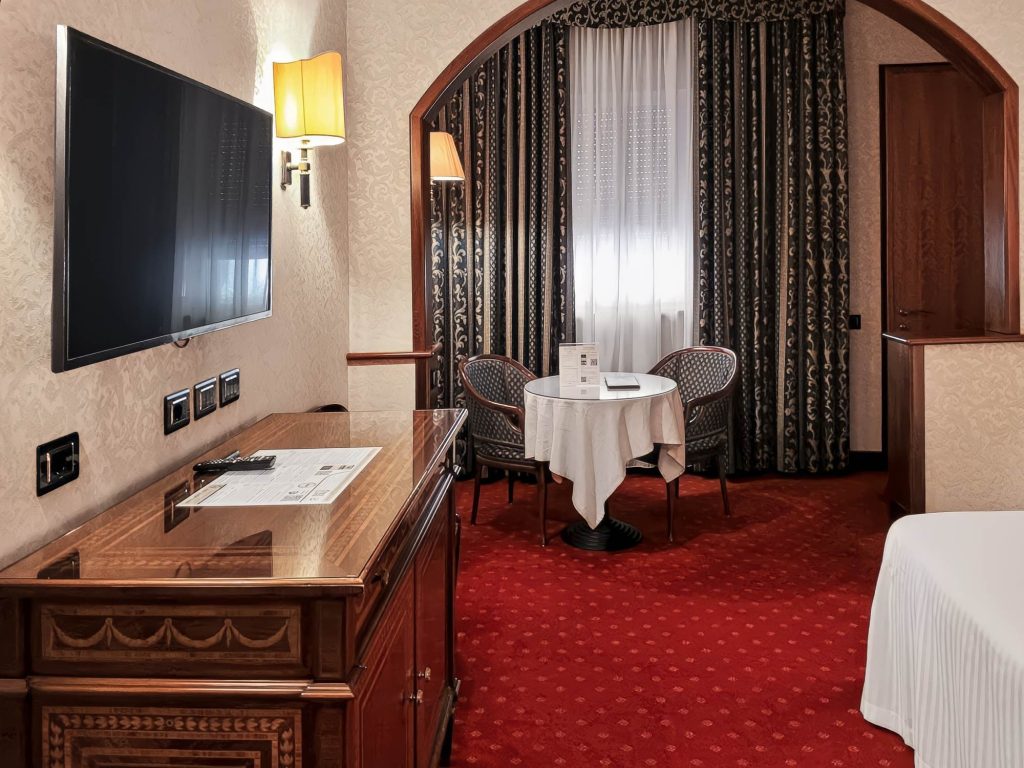 Classic Room con TV, mobile intarsiato e tavolino rotondo vicino alla finestra